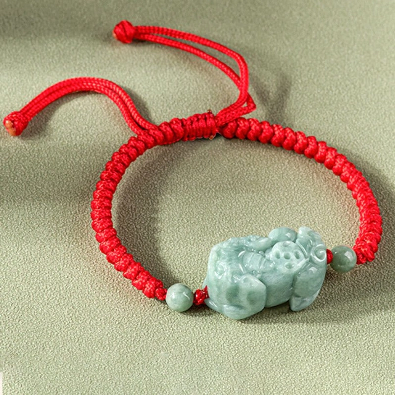Jade Pixiu protection bracelet showing braided cord and carved stone detail, angled view