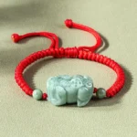 Handmade jade Pixiu red string bracelet with King Kong knot, flat lay view on gray background