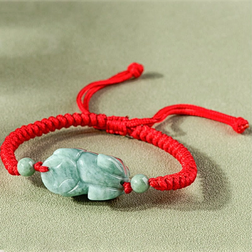 Jade Pixiu beast figurine on braided red cord, side profile close-up view