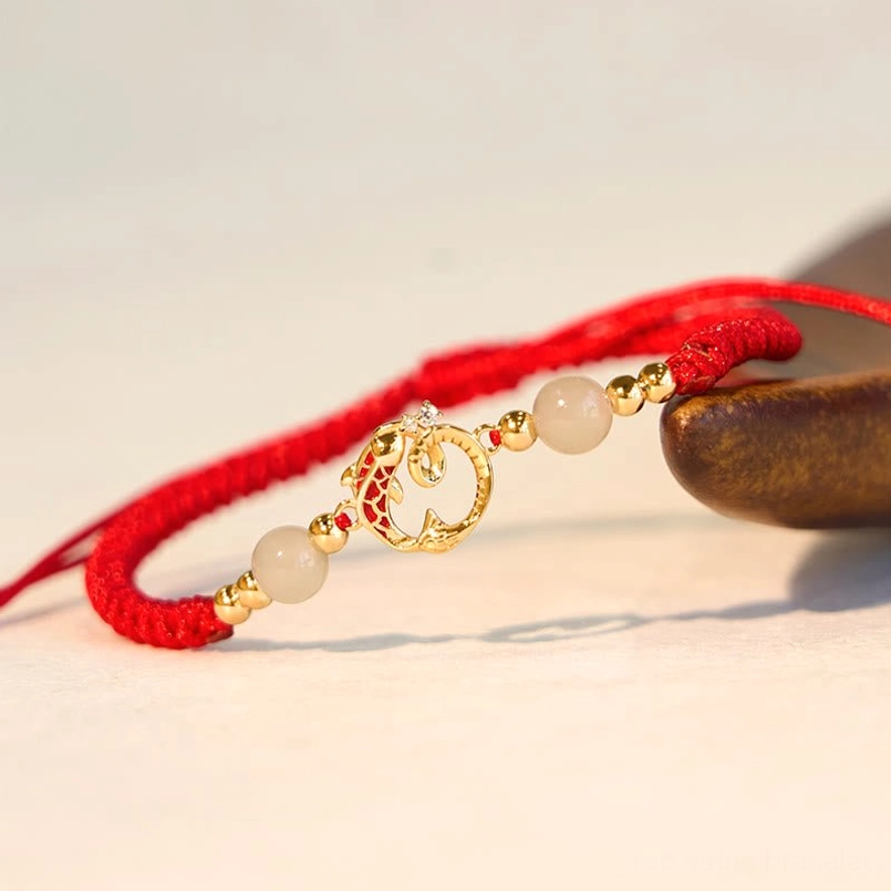Red braided string jade protection bracelet with detailed gold snake koi charm side close-up
