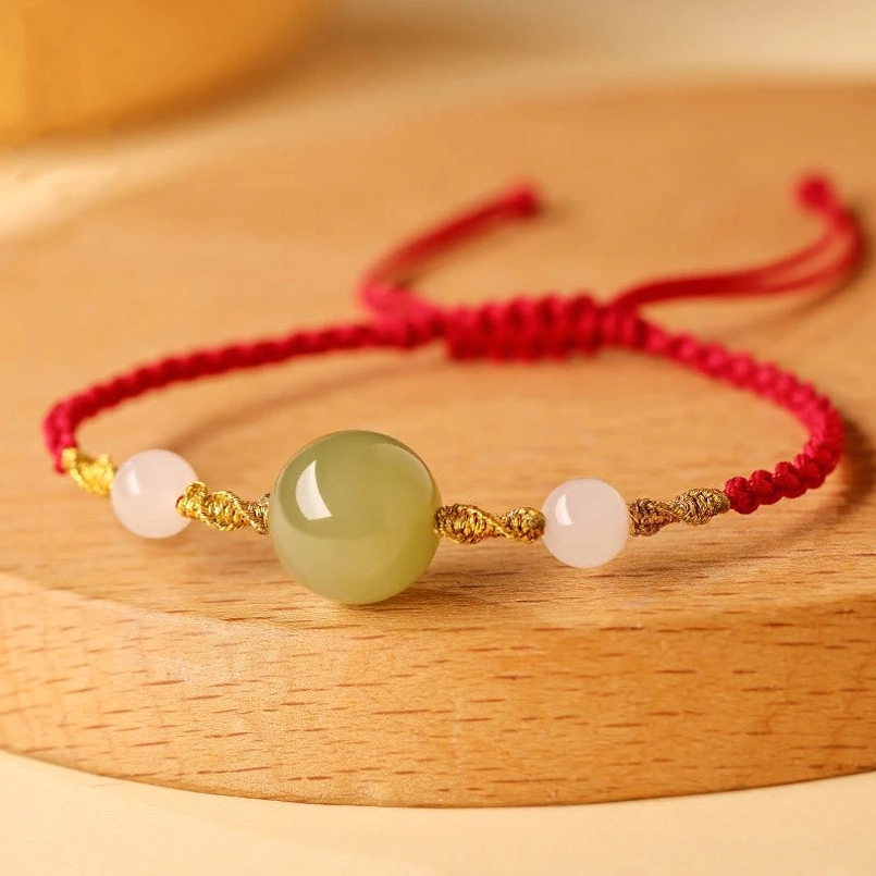 Hetian jade red rope bracelet on round wooden tray, artisan presentation