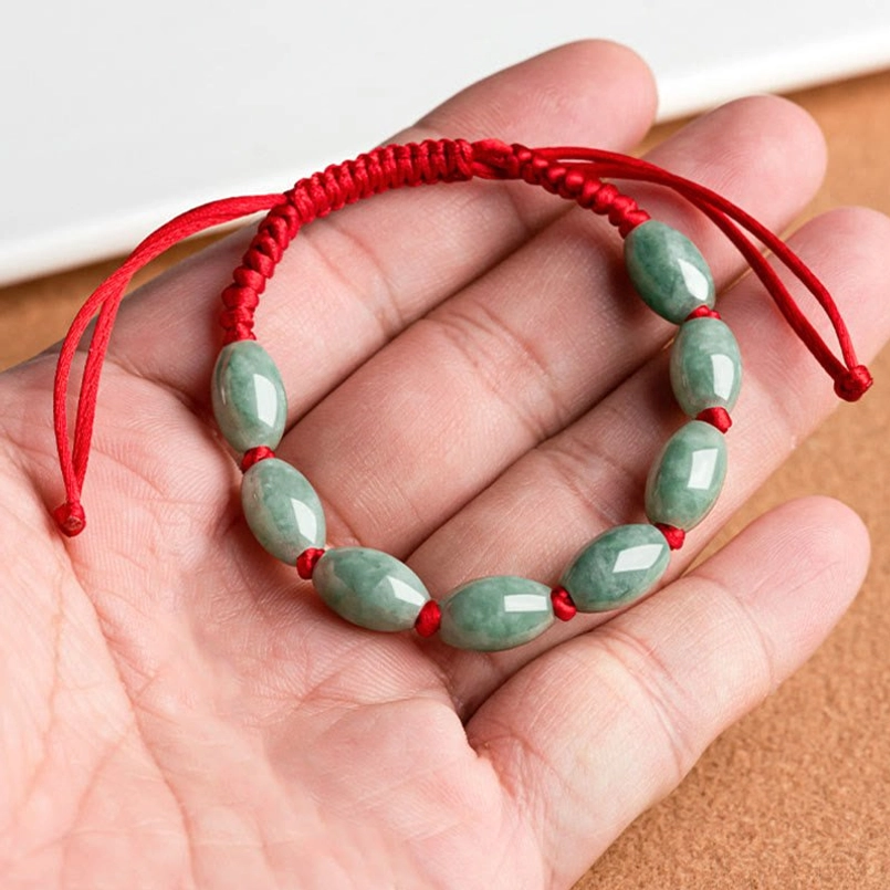 Hand held close up of jade red string bracelet showing bead structure