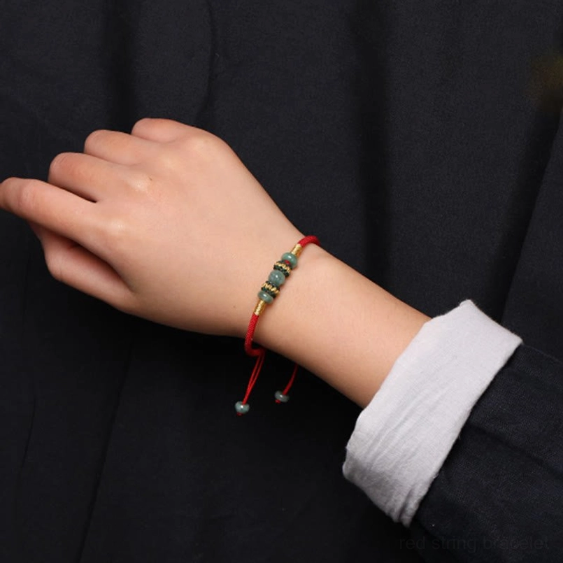 Jade abacus red string bracelet neatly fitted against white shirt cuff on wrist