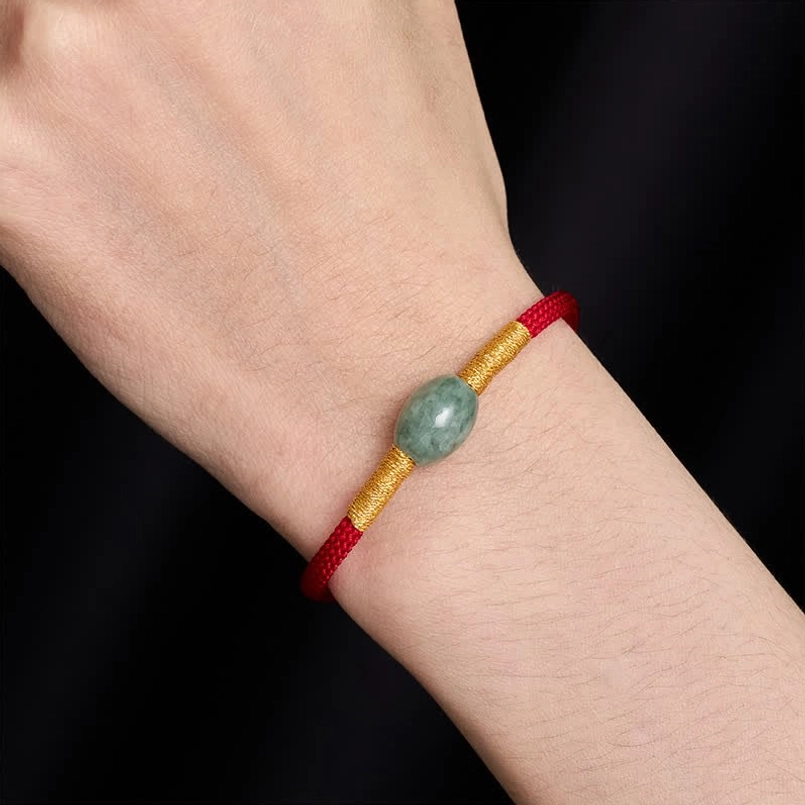 Red string jade bracelet on wrist showing protection and prosperity design