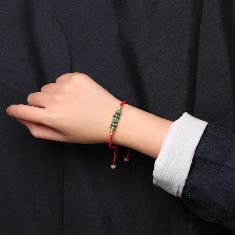 Jade abacus red string bracelet worn on wrist with white shirt cuff