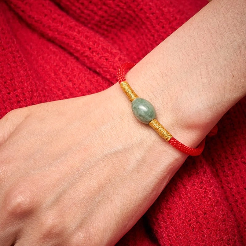 Jade red string protection bracelet worn on wrist with gold thread details