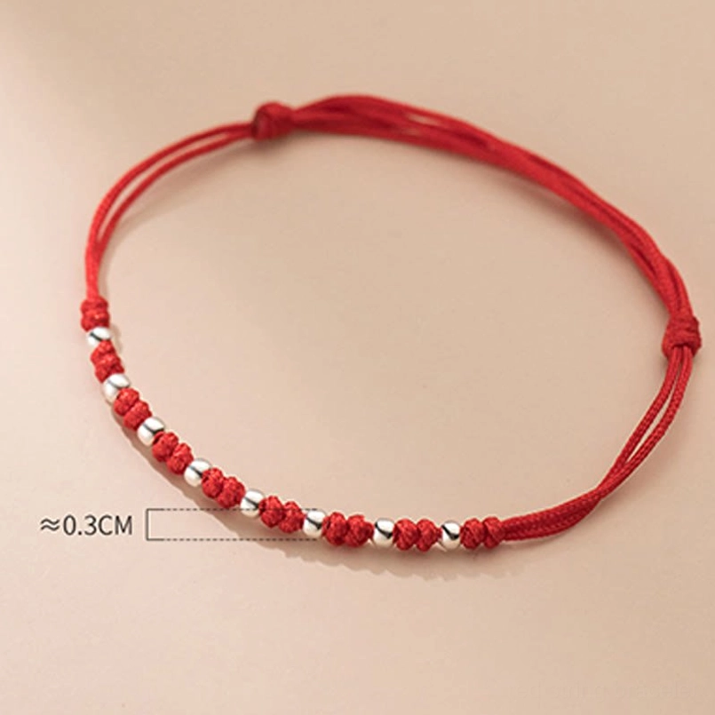 Red string kabbalah protection bracelet with silver beads displayed on minimalist background