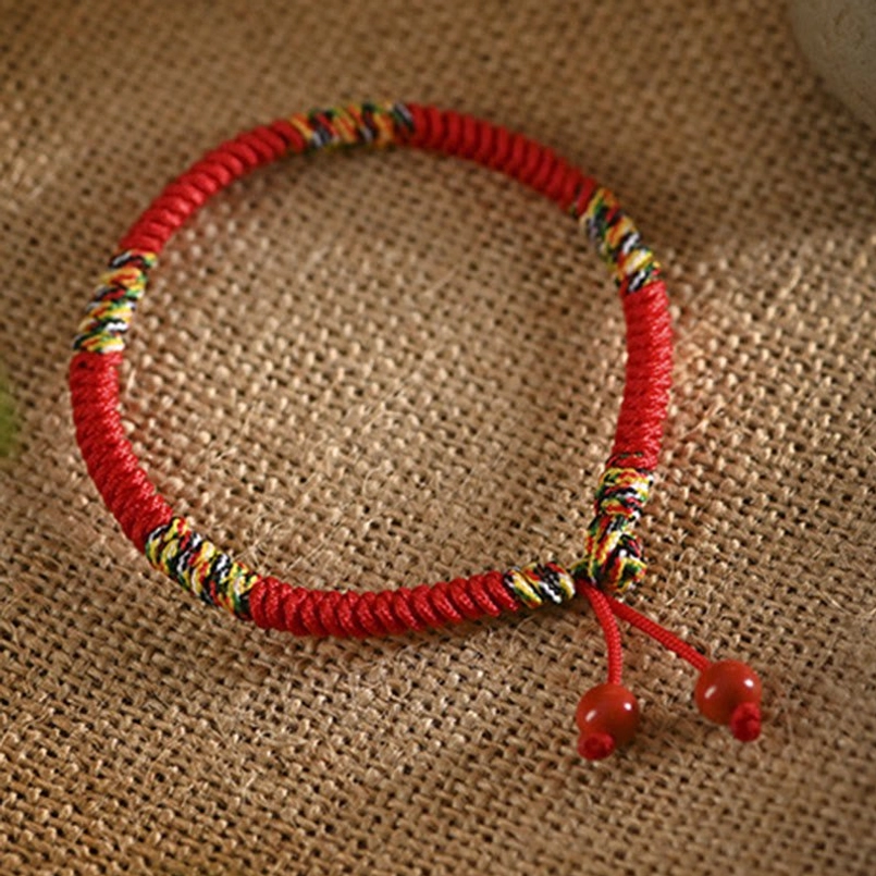Five colors king kong knot red string bracelet overhead view on burlap fabric showing braided knot design