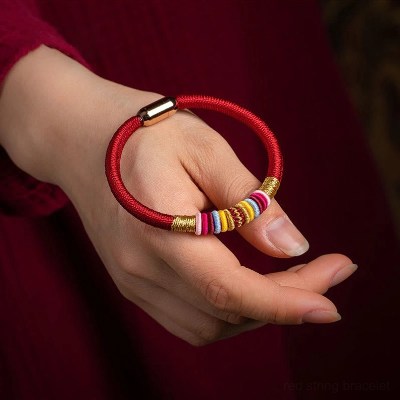 Tibetan King Kong Knot bracelet worn on woman's wrist showing red cord and colorful woven wraps