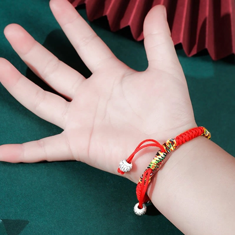 Close-up of colorful braided King Kong knot kids bracelet with silver beads and red rope details
