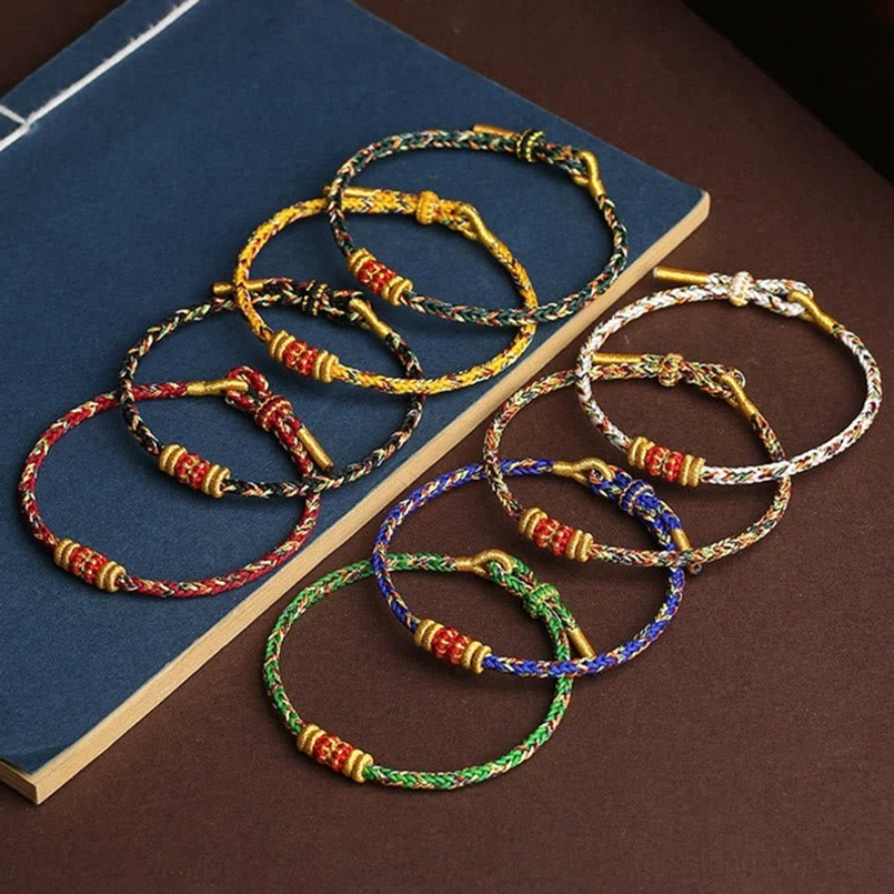 Multiple color options of King Kong Knot lucky bracelets with matching gold knot decorations flat lay