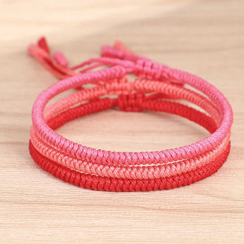 Braided red string protection bracelet overhead view wooden texture background adjustable knot
