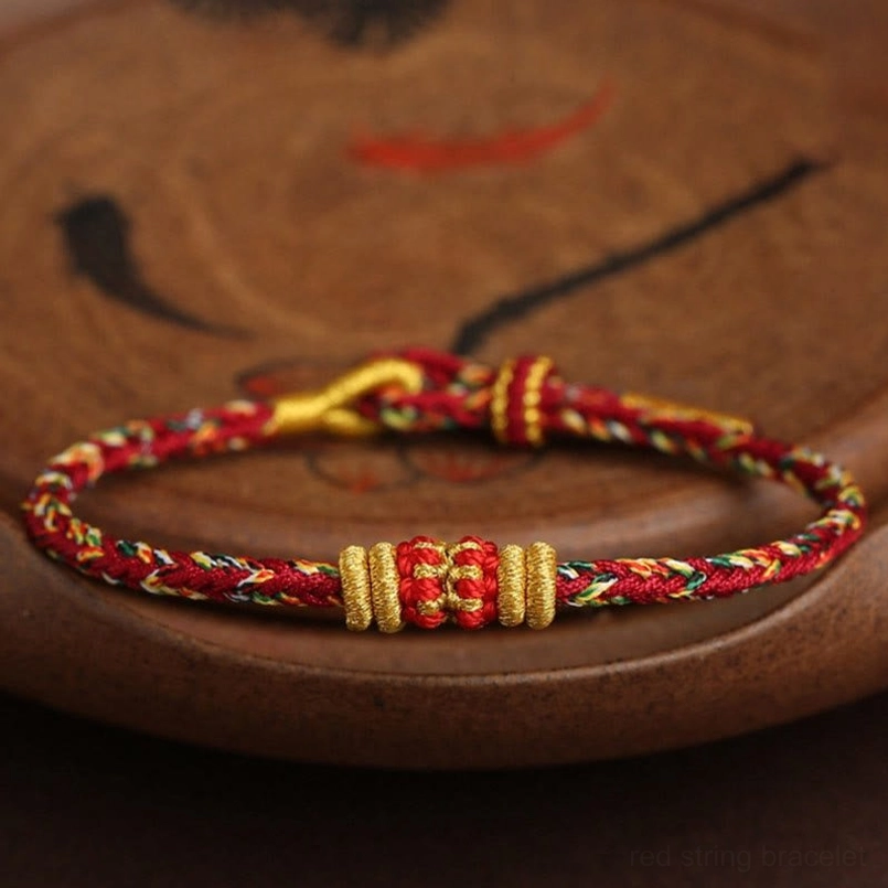 Overhead close-up of handmade King Kong Knot red string bracelet with double gold knot sets