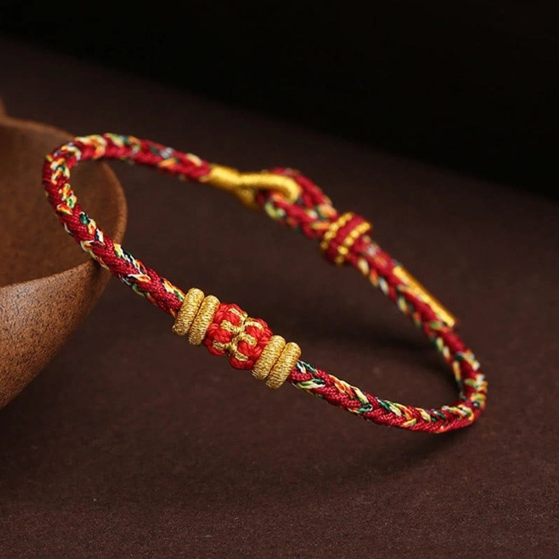 Angled side view of multicolor King Kong Knot Tibetan braided lucky bracelet on wooden surface