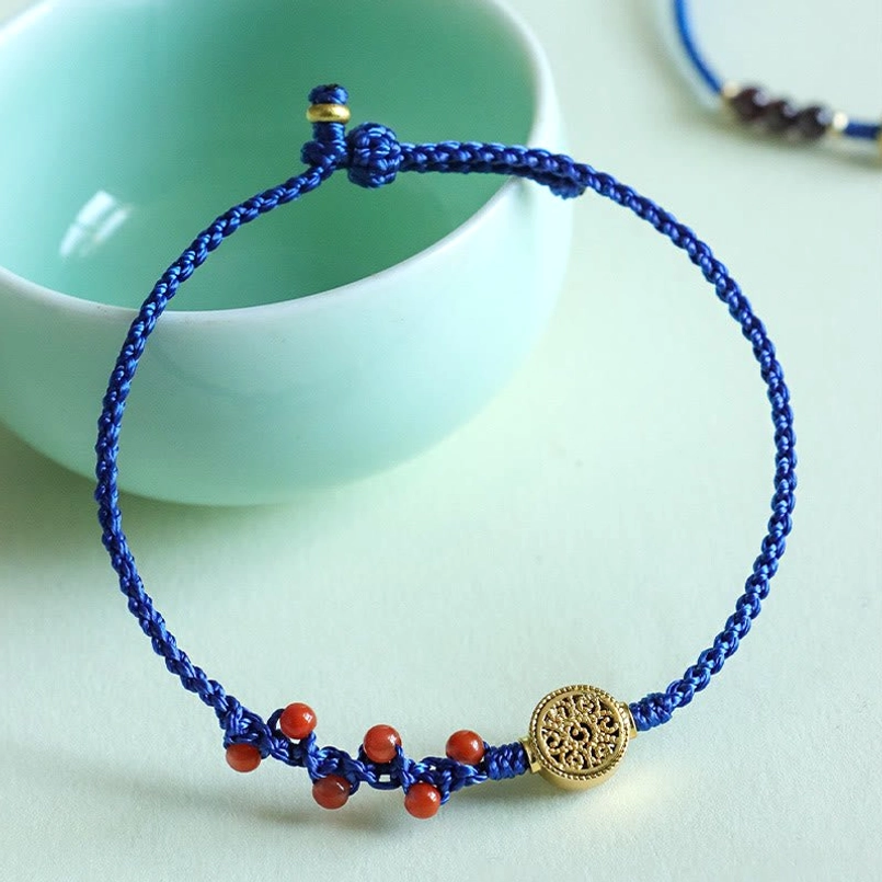 Klein blue string bracelet with south red agate copper circle charm flat lay by green teacup