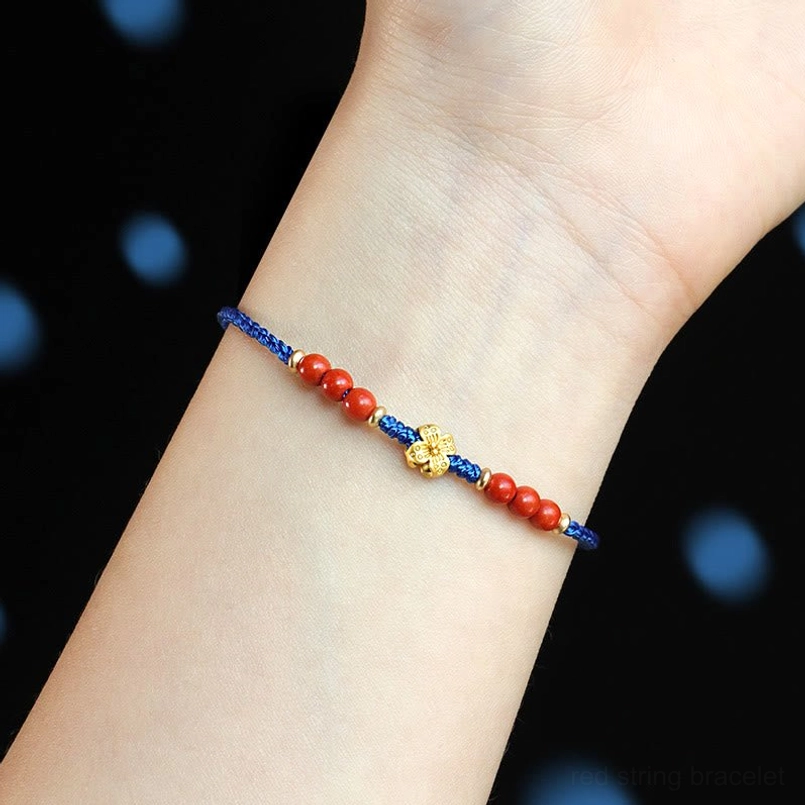 Wearing Klein blue string bracelet with red agate beads copper clover charm on wrist close up