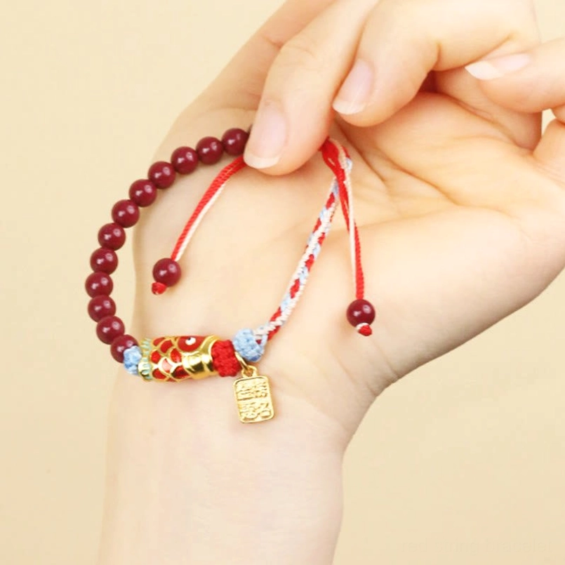 Red string cinnabar koi bracelet worn on hand showing adjustable fit and beads