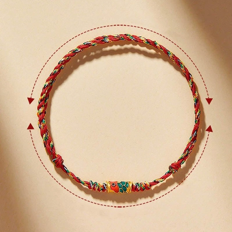 Flat lay of adjustable red koi fish bracelet showing size markers and enamel charm on beige