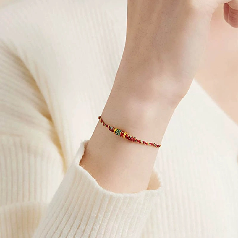 Side view of delicate red and yellow braided koi fish bracelet on wrist with natural setting