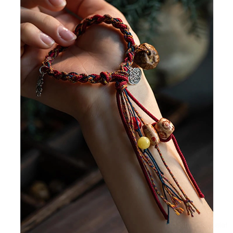 Red string bracelet close-up showing silver cloud charm colorful tassels and mixed ceramic beads