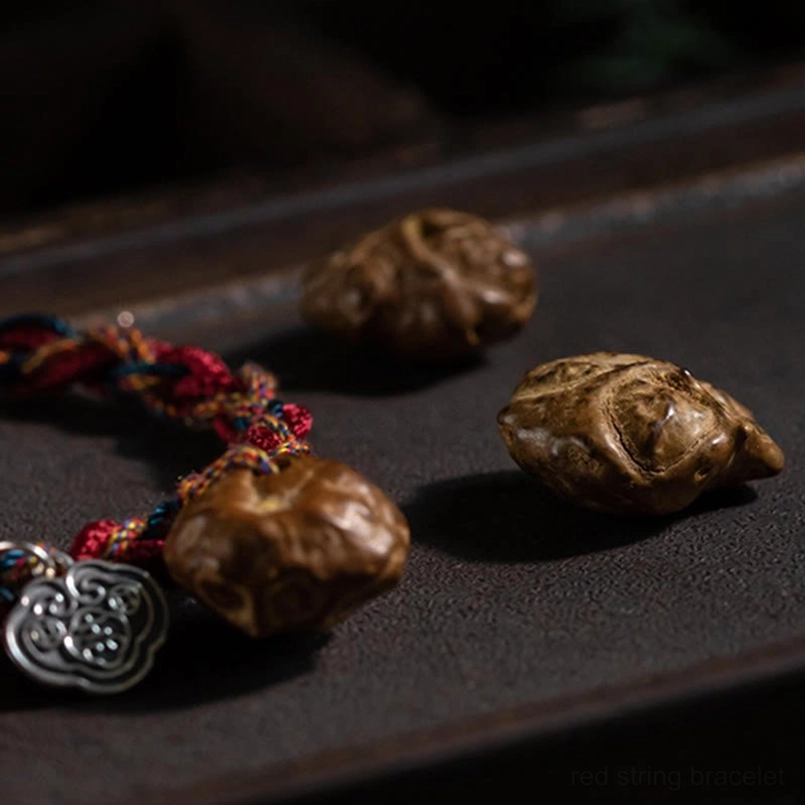 Close-up side view of red string bracelet with silver cloud charm and hand-carved wood beads detail