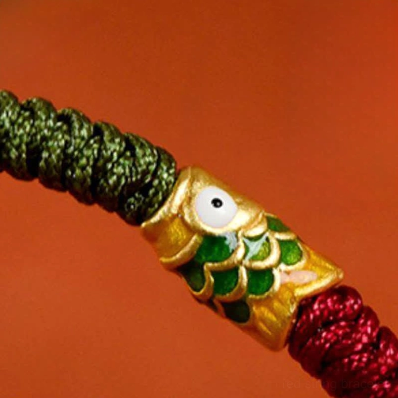 Red green braided koi fish bracelet worn on wrist with ceramic backdrop
