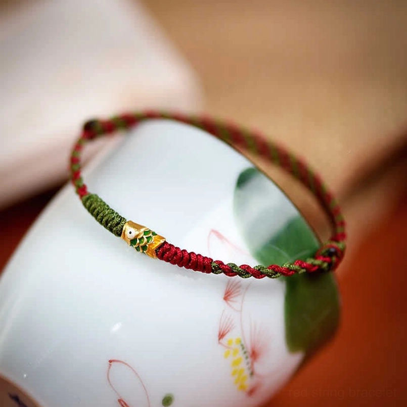 Braided red green koi fish bracelet side angle view with ceramic backdrop