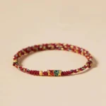 Red and colorful koi fish prosperity bracelet with enamel charm and golden bead accent on beige background