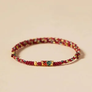Red and colorful koi fish prosperity bracelet with enamel charm and golden bead accent on beige background