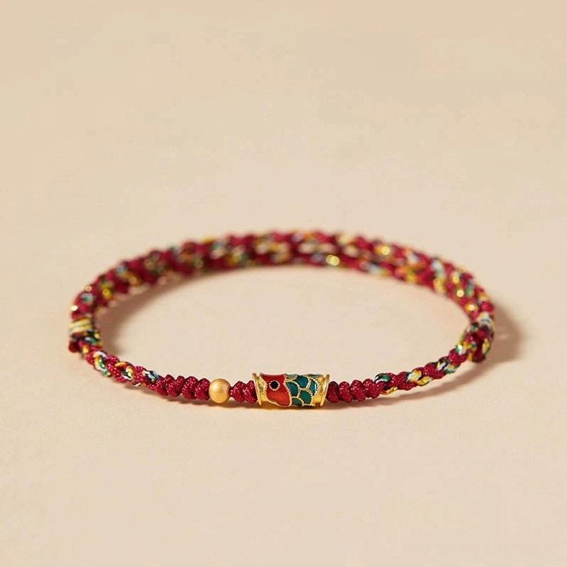 Red and colorful koi fish prosperity bracelet with enamel charm and golden bead accent on beige background