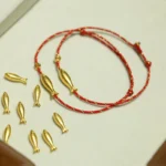 14K gold plated koi fish red string bracelets with adjustable knot closure shown in overhead view