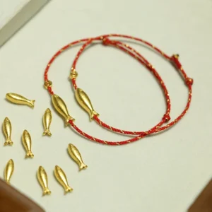 14K gold plated koi fish red string bracelets with adjustable knot closure shown in overhead view