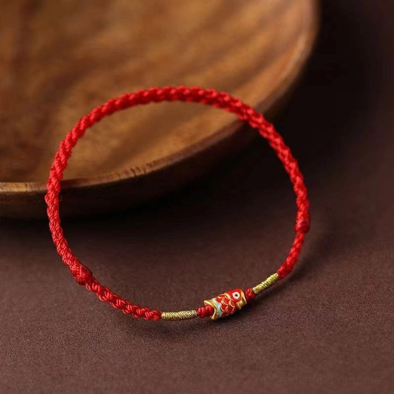 Side View of Koi Fish Red String Bracelet on Wooden Plate Background