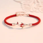 Rose gold koi fish red string couple bracelet with adjustable metal chain on lace background