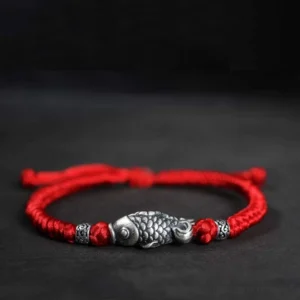 Red woven koi fish sterling silver bracelet with vintage silver charm and decorative beads on dark background