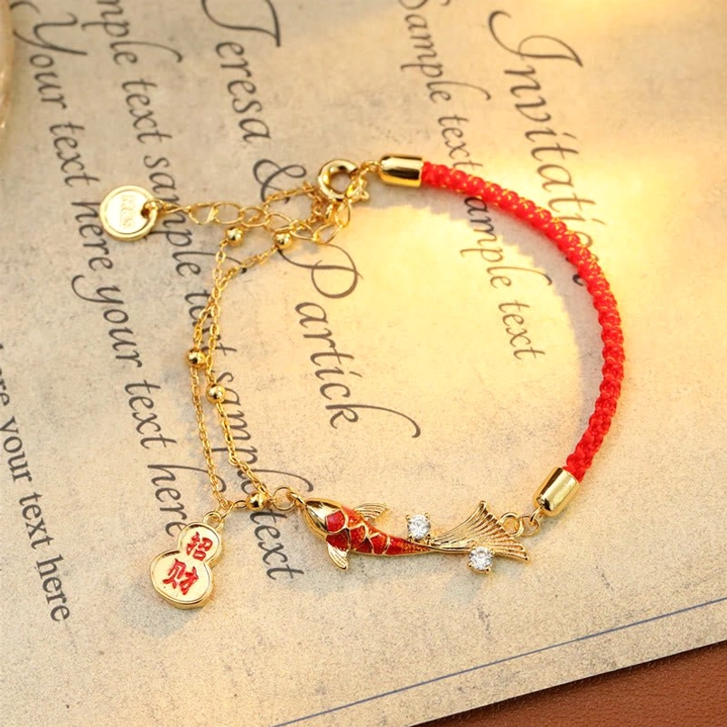 Zhao cai koi red string luck bracelet with enamel charm and woven red rope on calligraphy background