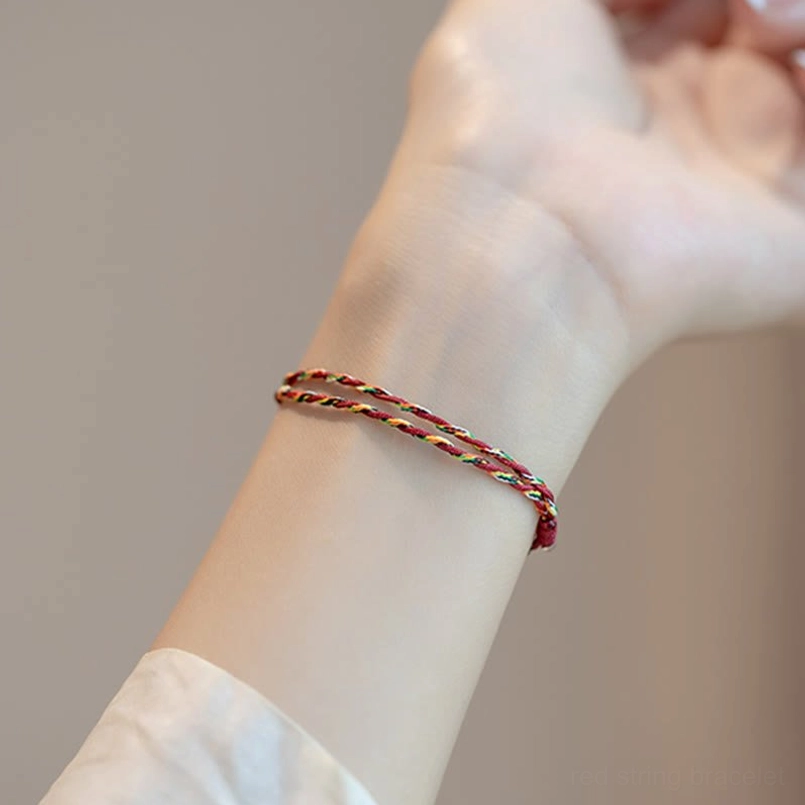 Koi fish themed bracelet with silver charm multicolored braided cord flat lay on white background