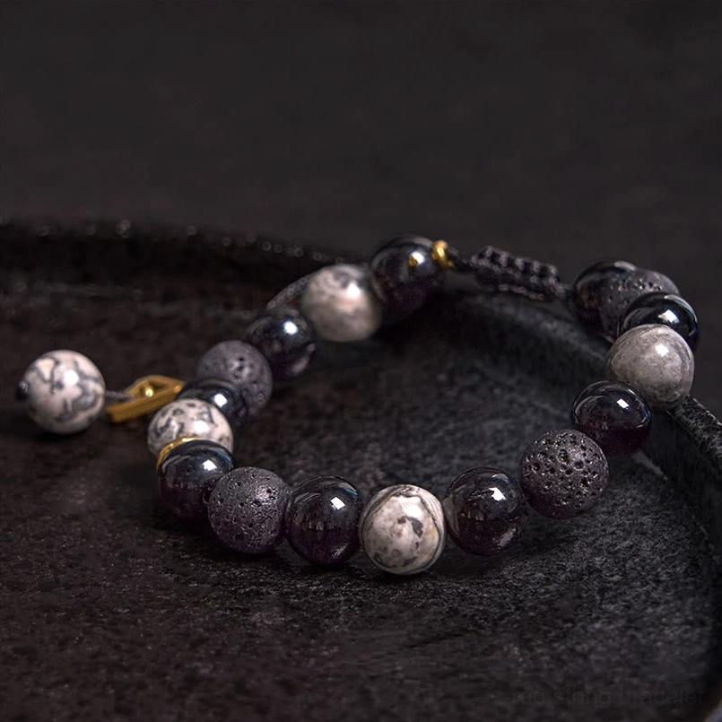 Adjustable black stone bracelet with pull cord and decorative end bead, dark background