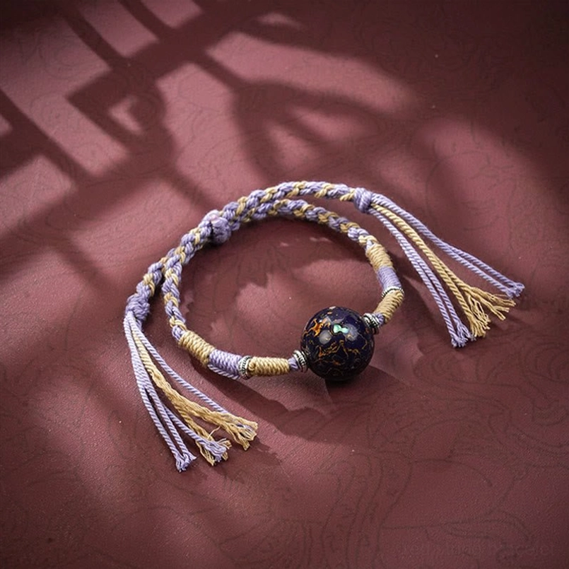 Lavender purple braided red string bracelet with dark patterned lacquer bead