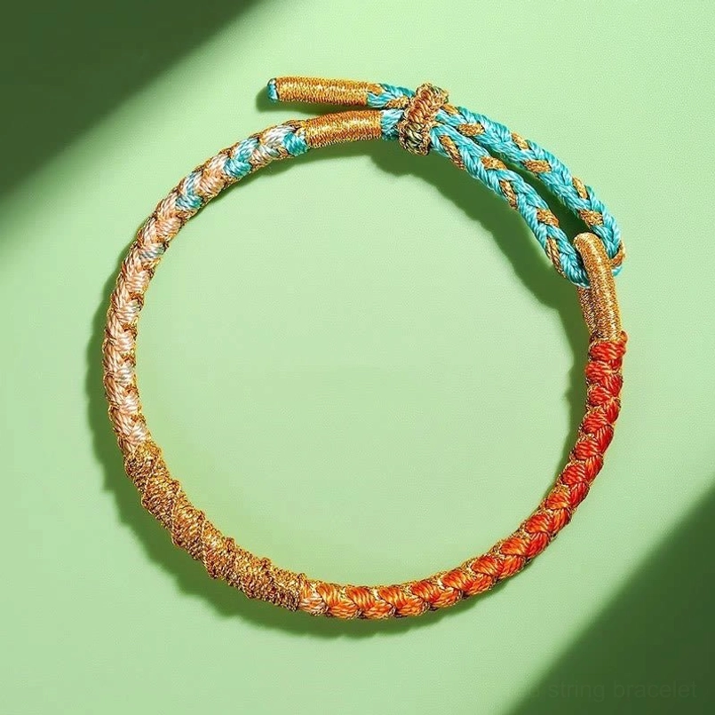 Light blue colorful twisted Tibetan protection bracelet with gold gradient braid on light background