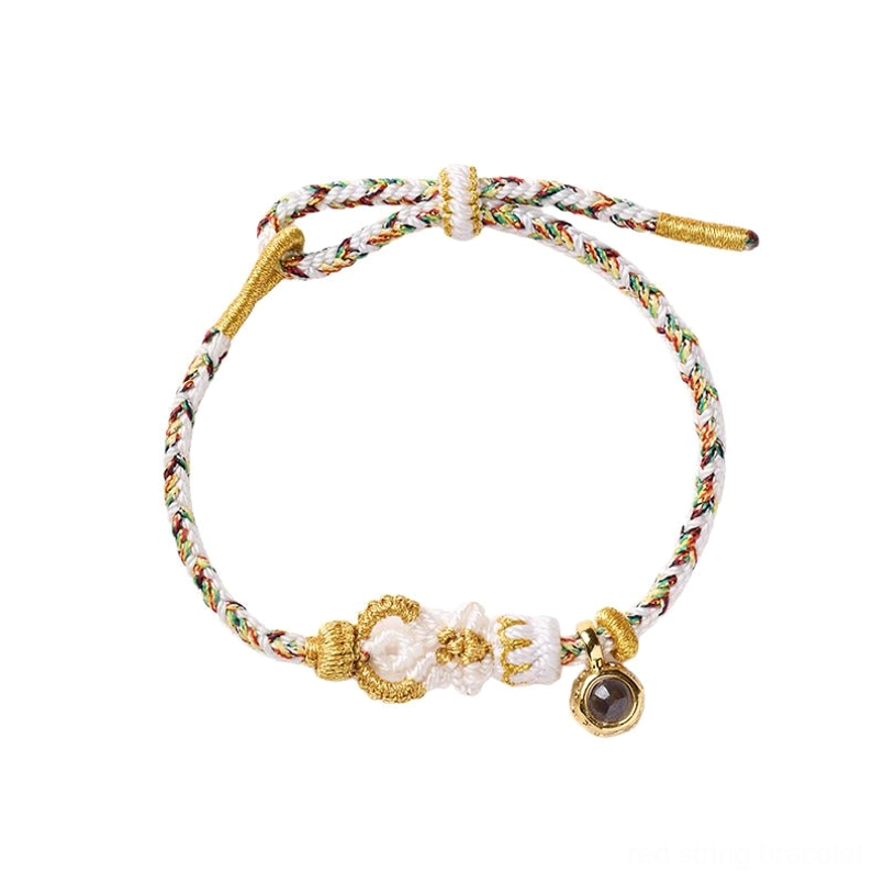 Light tone braided Buddha knot red string bracelet with black charm on white tabletop