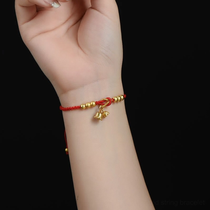 Slim red daily lucky bracelet worn on wrist with gold lily charm accent