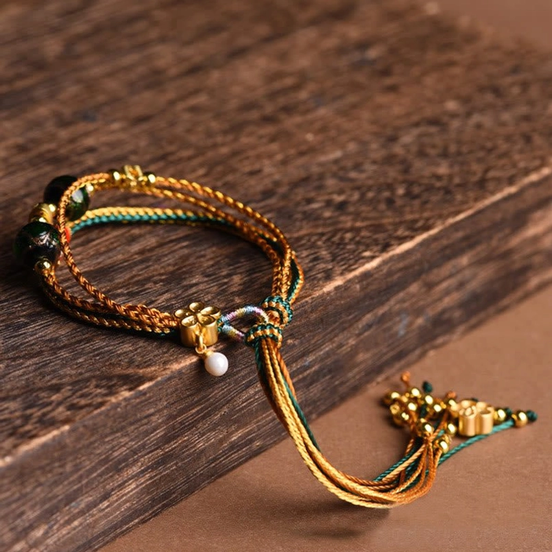 Multi-layered braided healing bracelet side view showing adjustable woven tail and white pearl accent