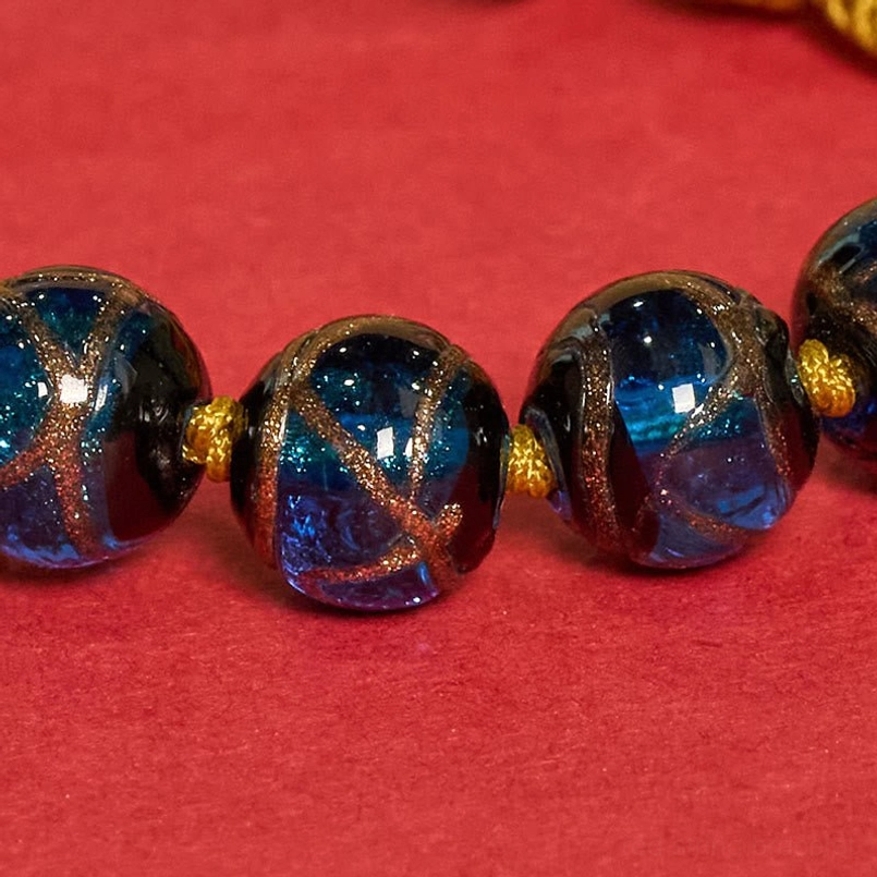 Premium liuli glass beads with gold glitter, close-up of faceted round bead design