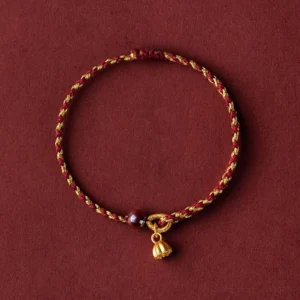 Handcrafted golden lotus pod charm red string bracelet with dark bead accent on dark red backdrop