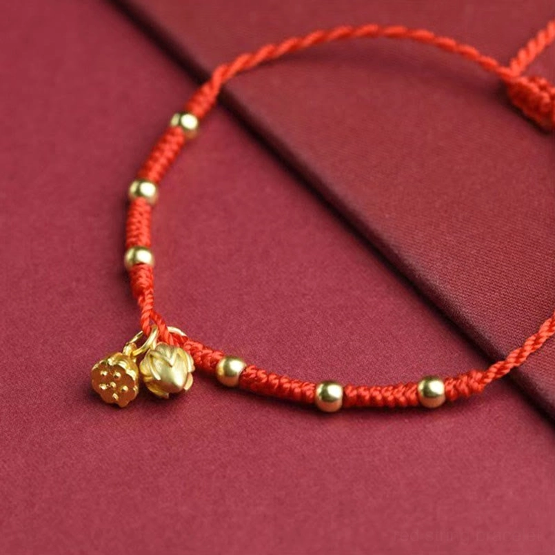 Close-up of red string lotus anklet showing intricate lotus and seed pod pendants with spaced gold beads