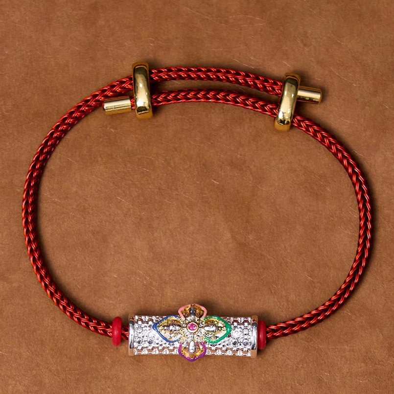 Red string bracelet flat lay showing adjustable design, copper flower charm, and protective cord