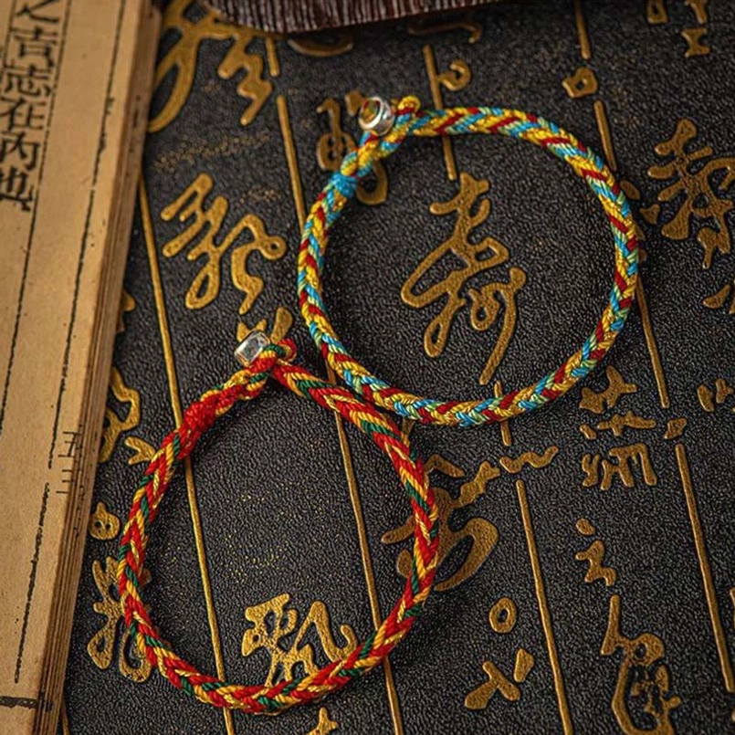Two color variants of woven lucky bracelets on dark background with Chinese longevity character