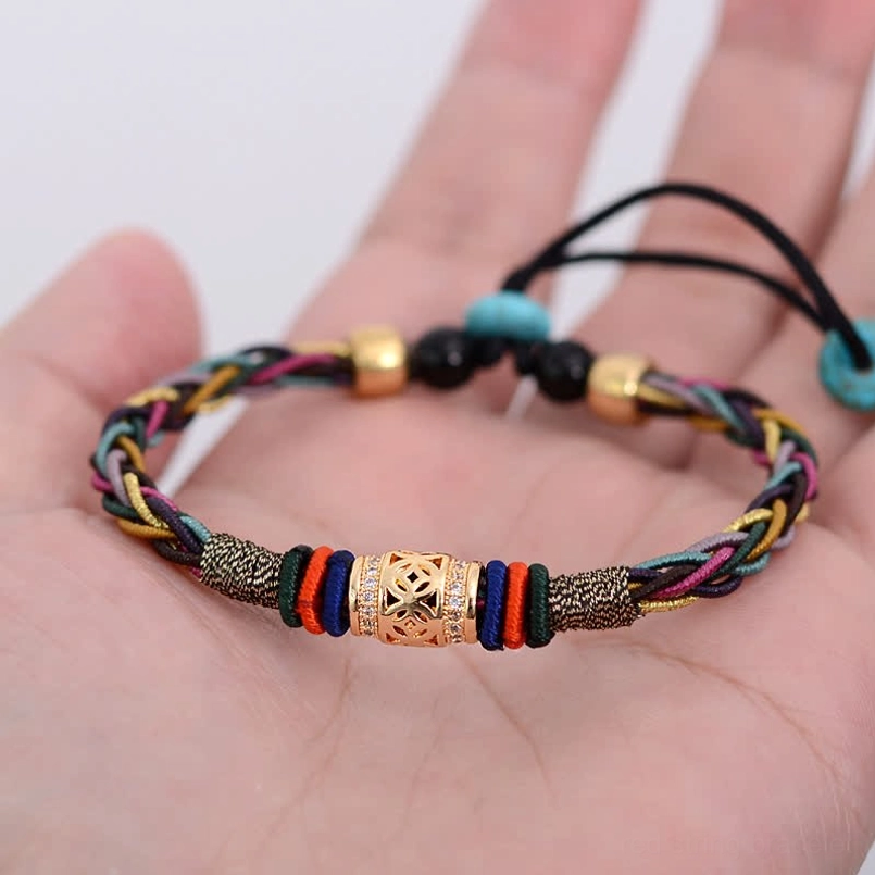 Handmade red string bracelet with copper coin held in palm showing detail