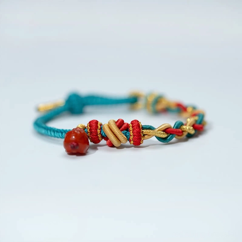 Four-strand woven lucky red string bracelet with red agate Pixiu charm side flat lay